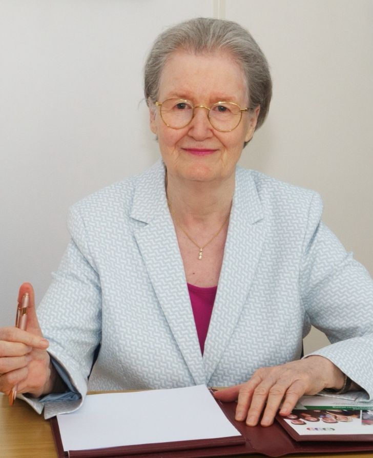 Das Bild zeigt eine Person im Anzug, die ein Tablet hält. Über dem Tablet schweben mehrere Zahnrad-Symbole. Im Hintergrund ist ein Büro mit Stühlen und Tischen zu sehen.